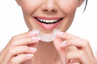 woman putting in clear aligners in Fort Collins