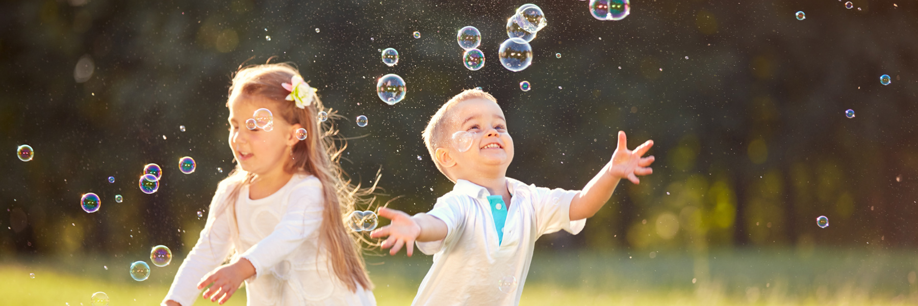 Two happy young children playing outdoors chasing bubbles, fort collins co