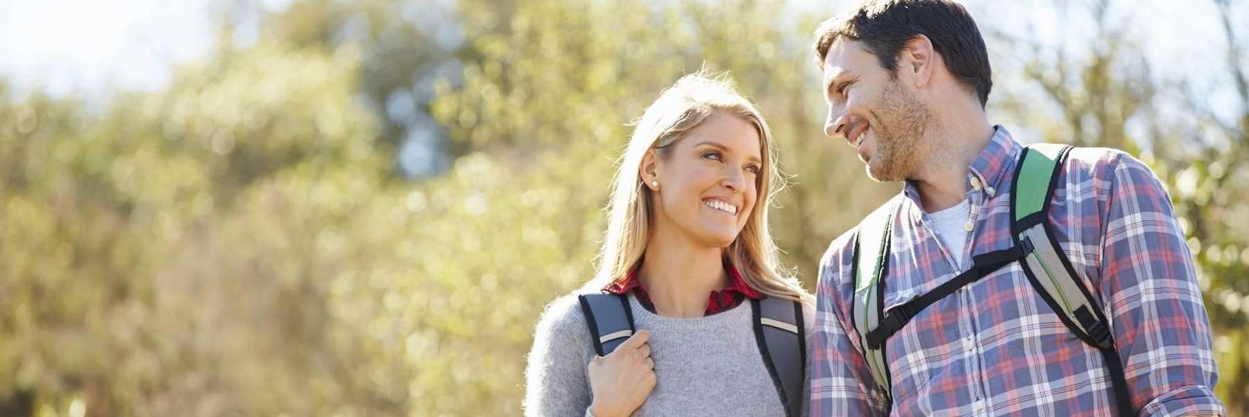 Couple smiling at each other with backpacks on outside, fort collins co