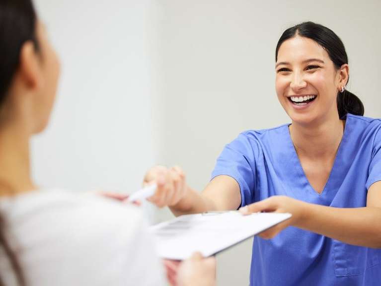 Dental hygienist handing a clipboard to a patient, fort collins co 