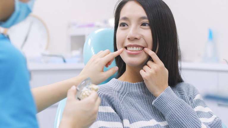 Asian women pointing at teeth in dental chair, fort collins co