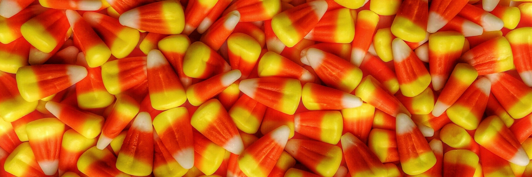 Large pile of Halloween candy corn in orange, yellow, and white colors